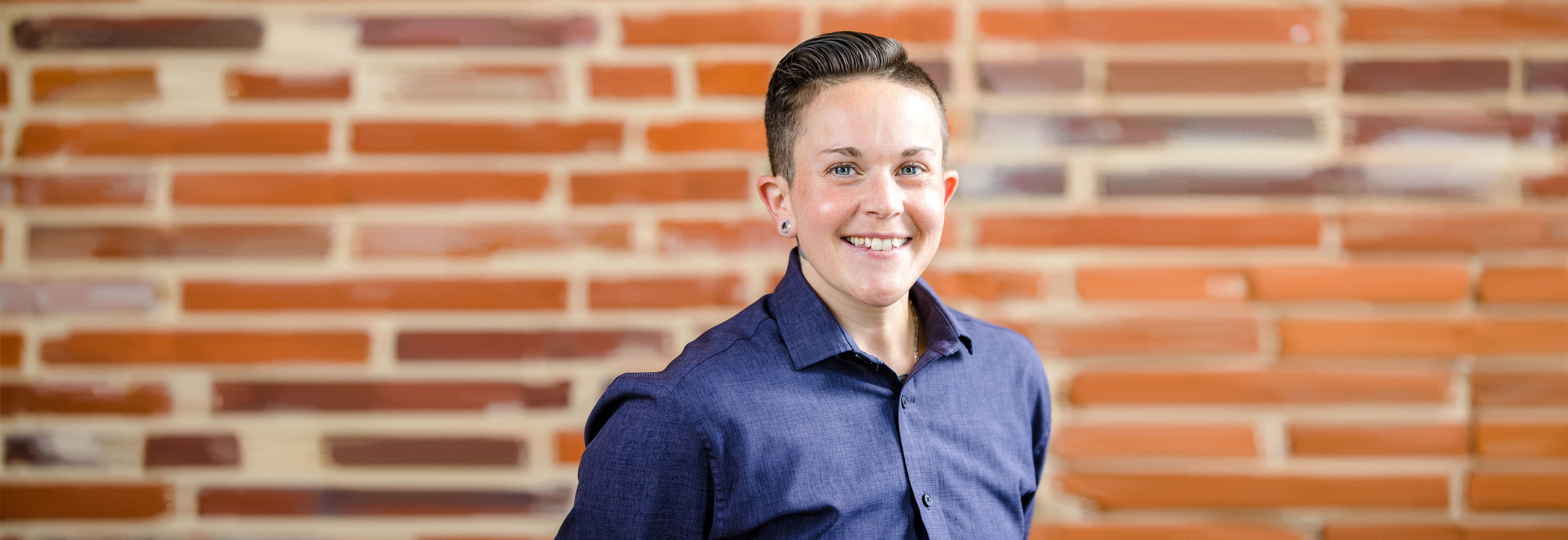 Sasha, a Capital One Customer Experience associate, stands in front of a blue background smiling next to a quote that says, "One connection can make a difference"