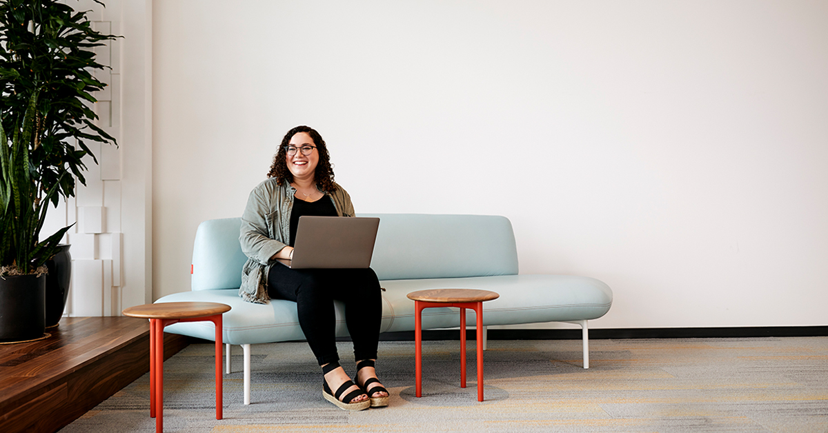 Capital One Intern, seated on a couch, working on a laptop