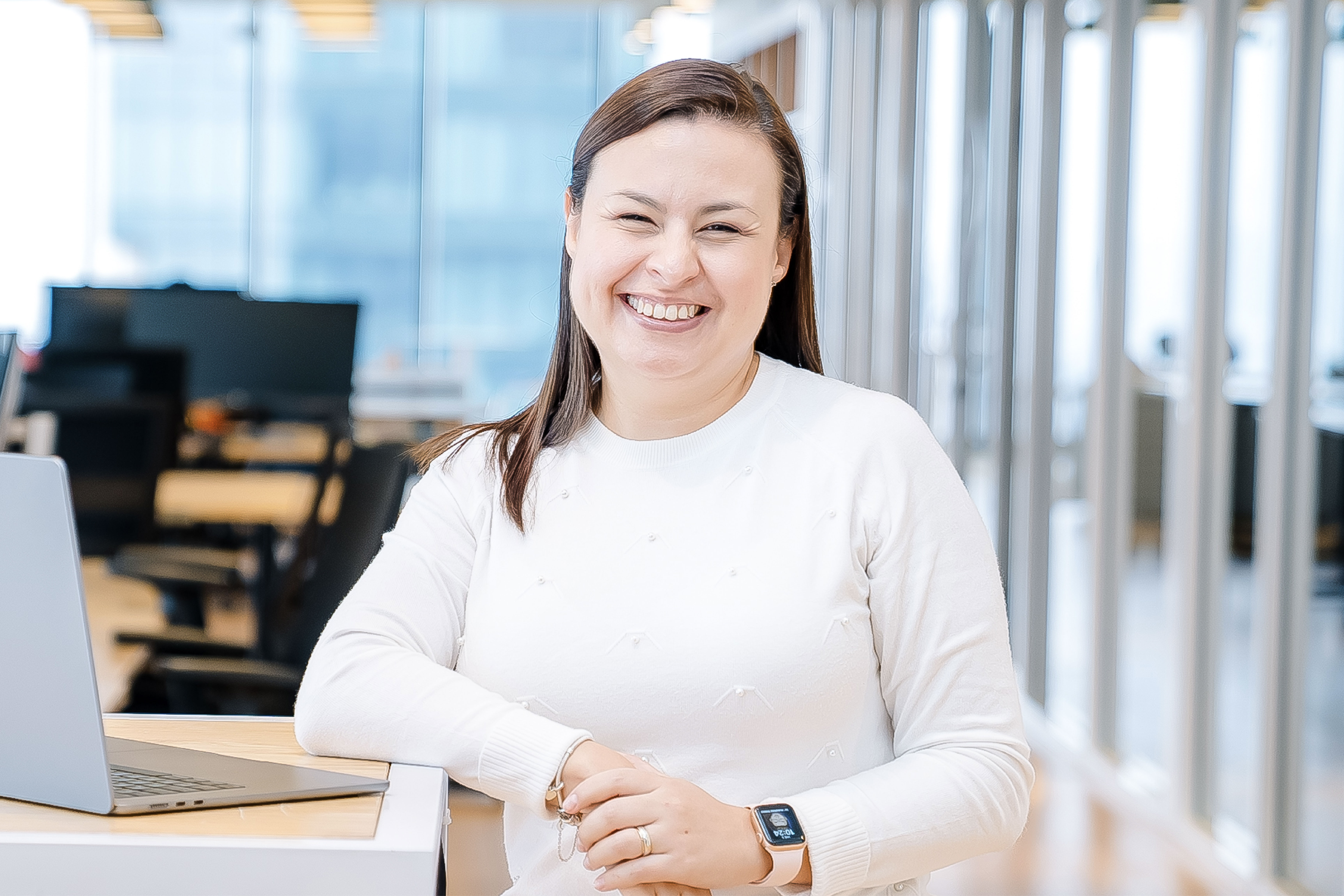 Capital One Mexico City associate stands at her laptop wearing a white shirt and smiles
