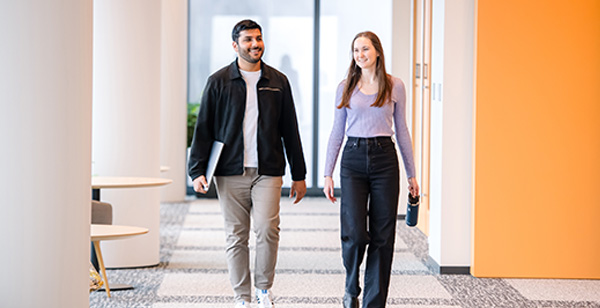 Two Capital One Strategy Consulting associates walk down a hall together