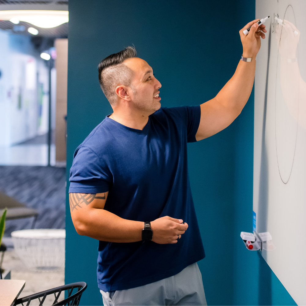 Capital One associate writes on a whiteboard wearing a dark blue tshirt