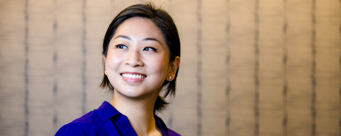 Capital One Tech associate Jessica stands in front of a tan wall and smiles