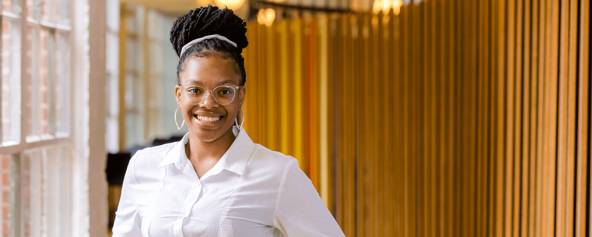 Capital One associate Khala stands in front of a yellow background and smiles