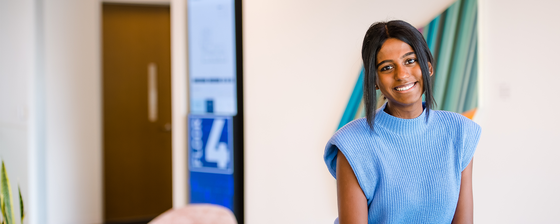 Capital One MRP associate leans against a table wearing a blue shirt