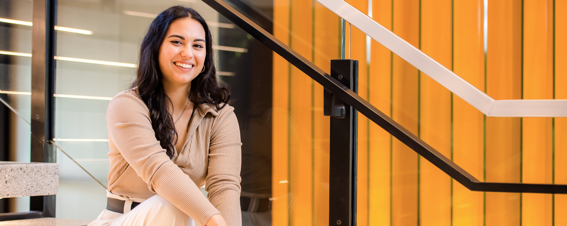 Capital One associate Jalen sits on the stairs and smiles