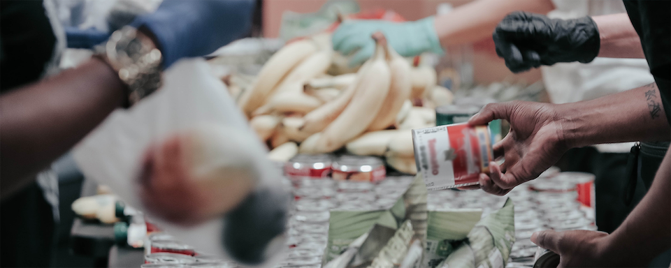 People handling a table of canned goods at a food drive with Capital One