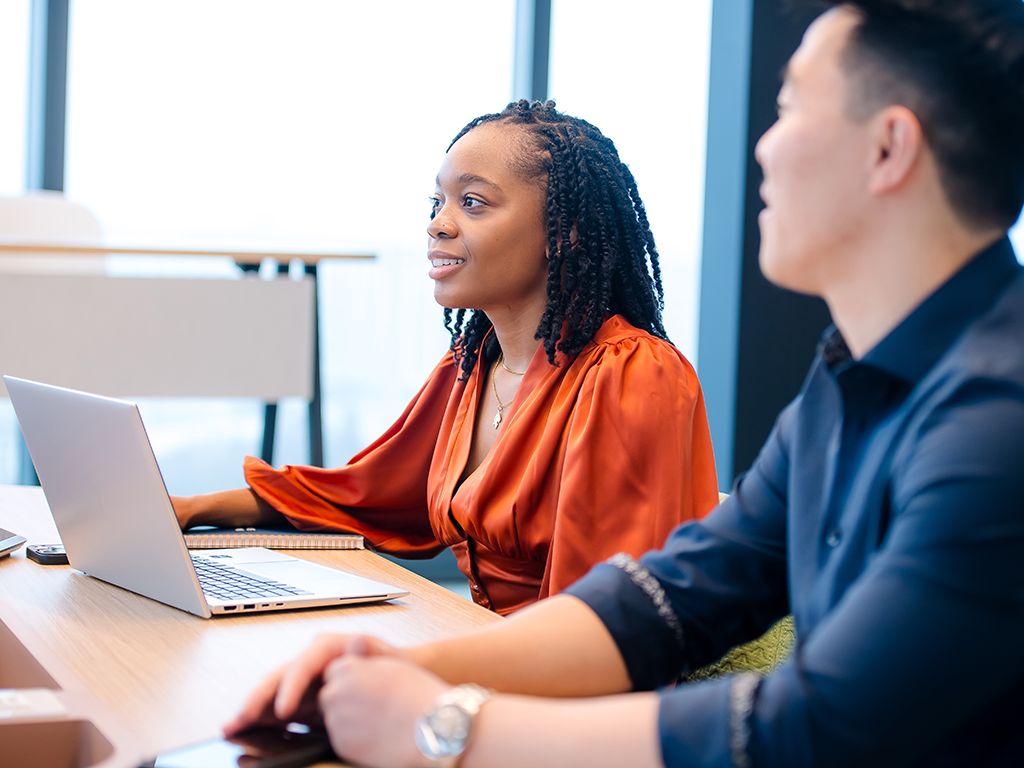 Two Capital One Strategy Consulting associates sit at a table with a laptop out