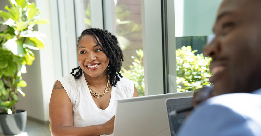 Capital One associates sit by a window and work on their laptops